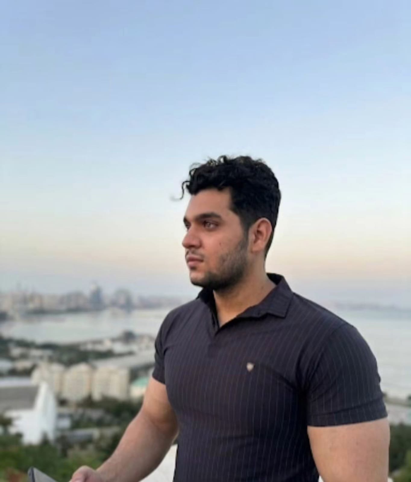 Sir Ibraheem looking out over a city and the sea at sunset