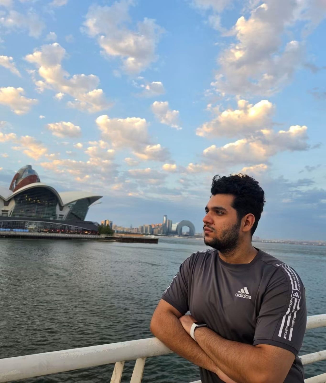 Sir Ibraheem leaning on a railing by the sea, under a sky full of clouds